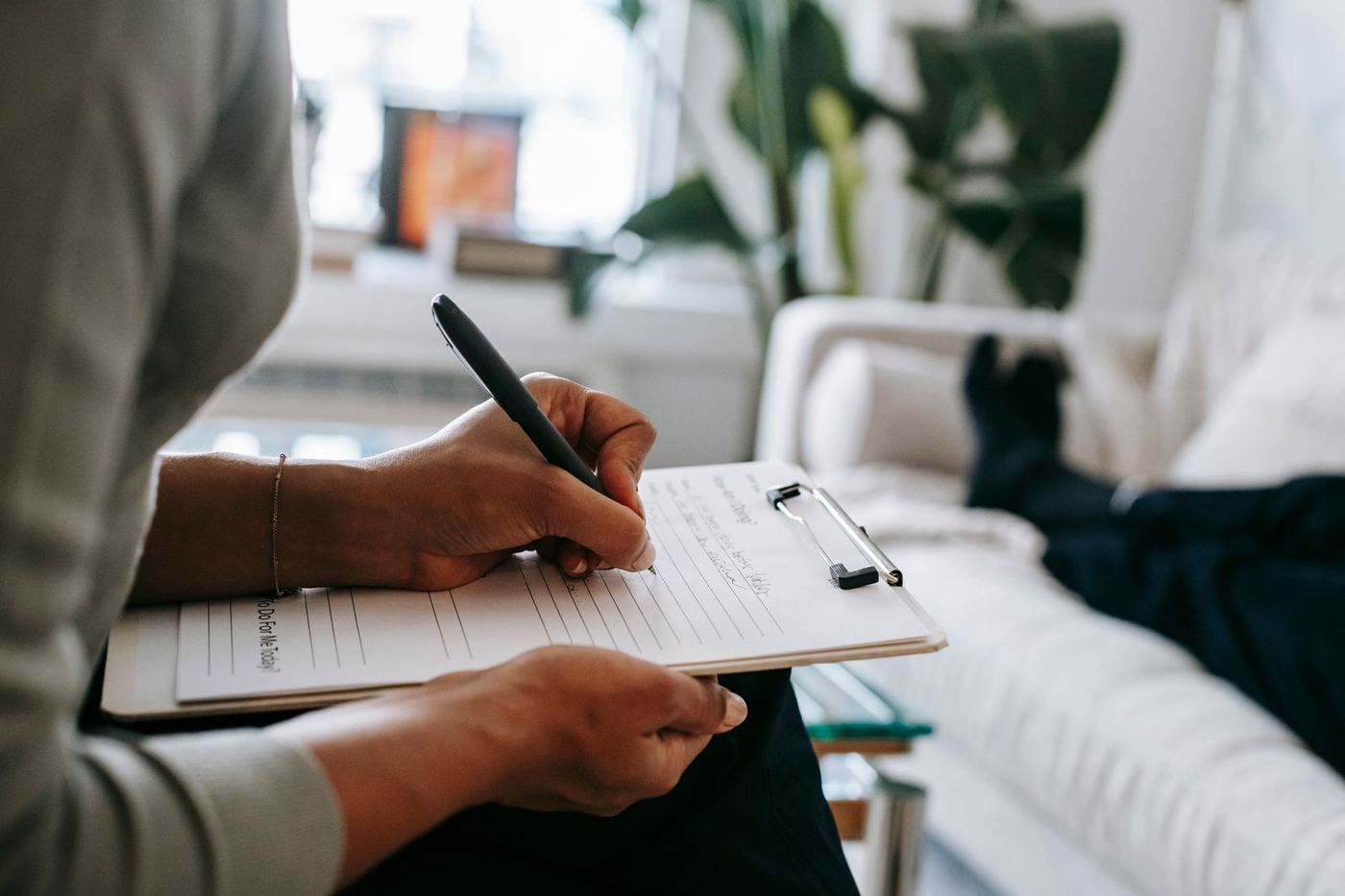 A clinician takes notes while a patient rests on a couch nearby